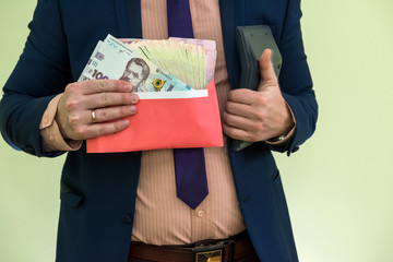 businessman receives money as a bribe in envelope. a man gives a whole bunch of hryvnia Ukrainian money in  envelope