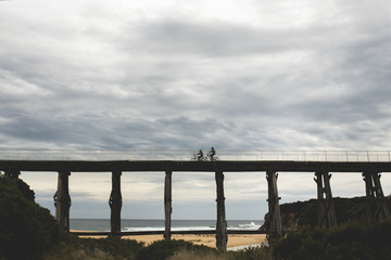 silhouette photos of bicycle riders on Kilcunda Bourne Creek Trestle Bridge on an overcast day in...