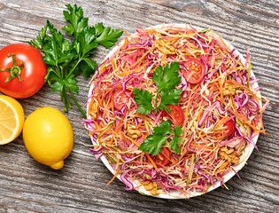 Vegan salad with red cabbage, cherry tomatoes, carrot, walnut. Home made vegetarian food. Clean eating concept on wood background. Tasty mix vegetable fresh cabbage salad. Top view.