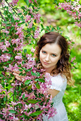 Naklejka premium Happy young girl enjoy peach blossom. Spring walk in the blooming garden