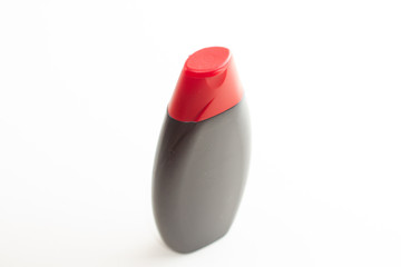 black empty bottle for liquid with red cap on a white background