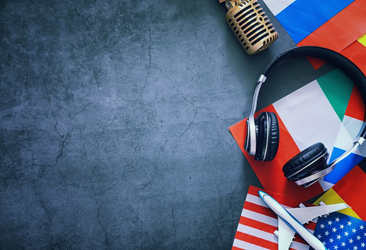 Learning foreign languages. Audio language courses. Background from countries flags and headphones on the table.
