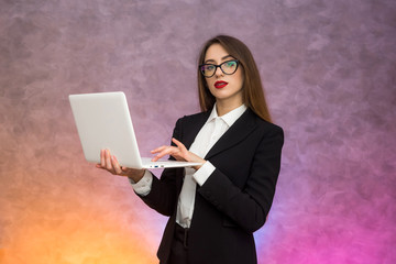 Attractive woman holding white laptop. Secretary or student or teacher posing on abstract background