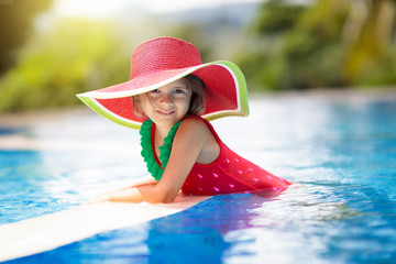 Child with hat in swimming pool. Tropical vacation