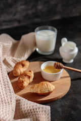 Croissants with honey and milk, close-up, on a dark background. French breakfast. Space for text. Dessert