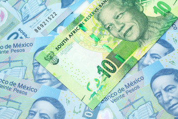 Fototapeta premium A close up image of a green ten rand bank note from South Africa in macro on a bed of Mexican twenty peso bank notes