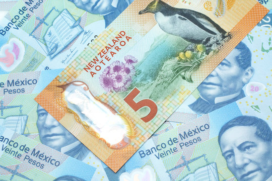 A close up image of a New Zealand five dollar bill with Mexican twenty peso bank notes in macro
