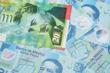 A close up image of a twenty shekel bank note from Israel on a background of Mexican twenty peso bank notes in macro