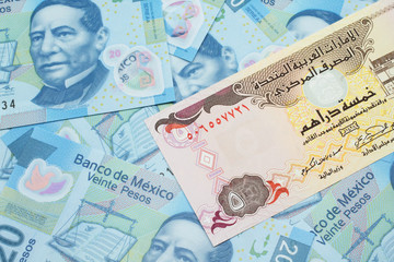 A close up image of a five dirham bank note from the United Arab Emirates on a background of Mexican twenty peso bank notes in macro