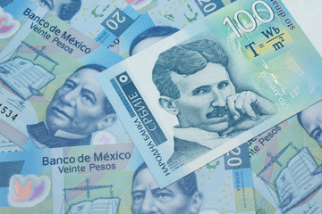Fototapeta premium A close up of a blue and white, one hundred Serbian dinar bank note on a background of Mexican twenty peso bank notes