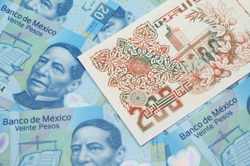 A macro image of a beige two hundred Algerian dinar bank note on a background of Mexican twenty peso bank notes
