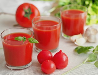 Three glasses with tomato juice decorated with basil. Selective focus