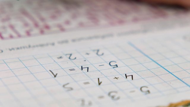Preschool boy toddler, holding pencil, writing or doing math homework at the table. Hands close up
