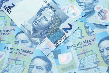 A blue two reais bank note from Brazil close up in macro with a background of United States Mexican twenty peso bills