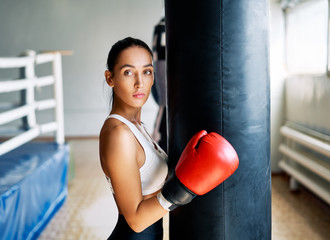 Sporty young woman wearing boxing gloves posing in gym