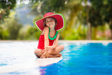 Child with hat in swimming pool. Tropical vacation