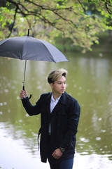 Spring rainy weather and a young man with an umbrella