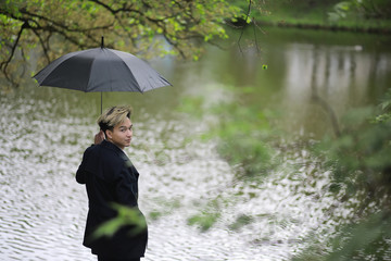 Spring rainy weather and a young man with an umbrella