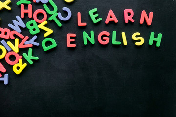 Obraz premium Learn English text near letters on black background top-down copy space