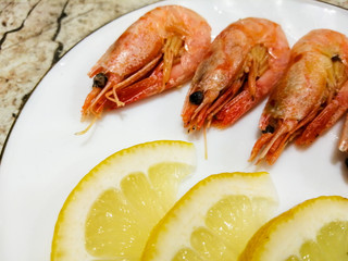 Boiled prawns with lemon and dill slices on a plate.