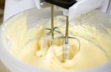 Close-up of a mixer making cream for preparing delicious home-made baking in the kitchen at home. - 327489818
