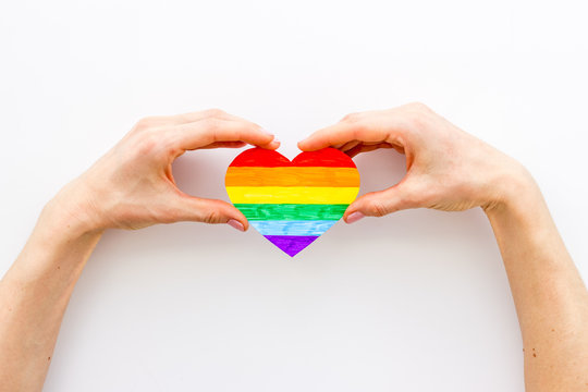 LGBT symbol. Rainbow heart in hands on white background top-down copy space