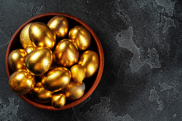 Golden Easter eggs on a black concrete background