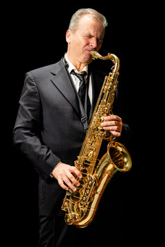 Musician playing saxophone (isolated on black background)