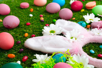Colored eggs and vibrant candies on grass. Easter composition