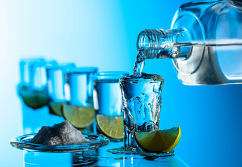 Tequila, salt and lime slices on a blue background.