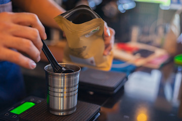 Attractive Asian barista the coffee shop owner preparing coffee for his customer. Film tone effected. Close-up and selective focused