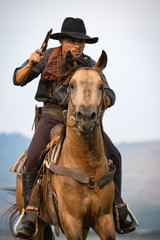 Obraz premium Cowboy man riding horse shooting
