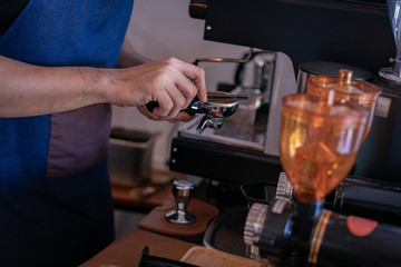 Attractive Asian barista the coffee shop owner preparing coffee for his customer. Film tone effected. Close-up and selective focused