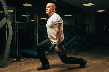 Fototapeta na wymiar Senior man in his fifties lifting weights in a gym