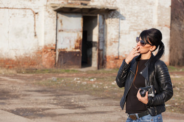 beautiful young girl photographed in black leather jacket with sunglasses and vintage camera