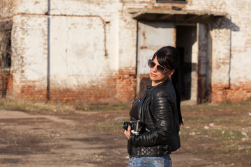 beautiful young girl photographed in black leather jacket with sunglasses and vintage camera