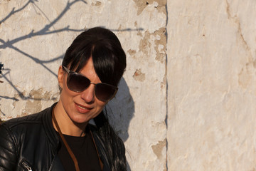 beautiful girl with sunglasses posing next to old wall