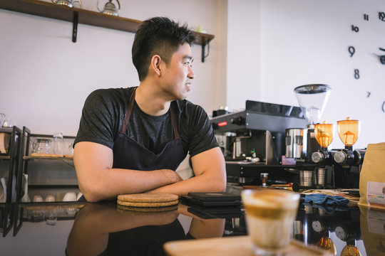 Cheerful success Asian barista! - The coffee shop startup owner stitting at the coffee counter