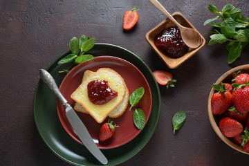 Toasts with strawberry jam for breakfast, rustic style 
