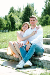 Girl hugging a guy sitting at a nature park