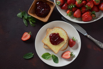 Toasts with strawberry jam for breakfast, rustic style 