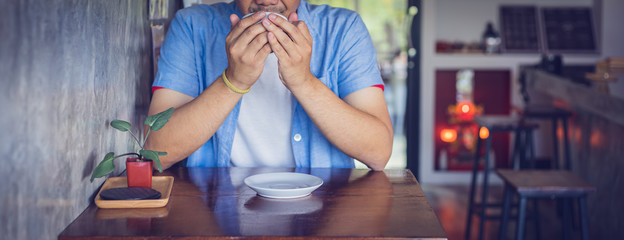 Attractive Asian man drinking coffee at the table in coffee shop. Film tone effected.