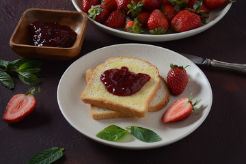 Toasts with strawberry jam for breakfast, rustic style 