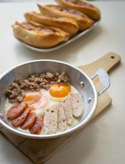 Fried eggs in a pan with meat on the wooden plate. The famous breakfast with Banh Mi - Vietnamese bun with meat.