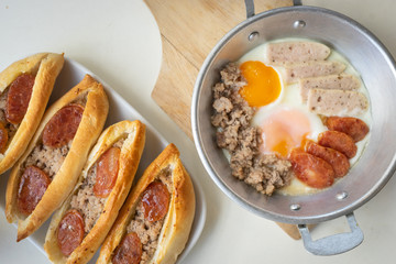 Fried eggs in a pan with meat on the wooden plate. The famous breakfast with Banh Mi - Vietnamese bun with meat. Top-view.