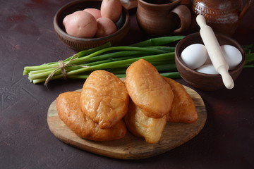 Russian Patties (Pasties, Hot Cakes, Pirozhki, Pies) on wooden cupboard . Traditional homemade fried pies with potatoes