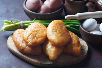 Russian Patties (Pasties, Hot Cakes, Pirozhki, Pies) on wooden cupboard . Traditional homemade fried pies with potatoes