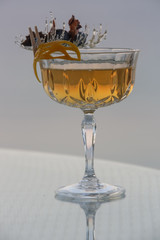 A glass of beautifully decorated whiskey cocktail with an orange peel on the bar counter	