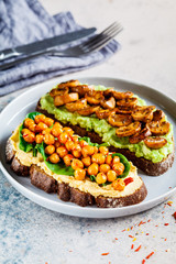 Vegan toasts with guacamole and mushrooms, hummus with chickpeas on rye bread. Healthy vegan food concept.