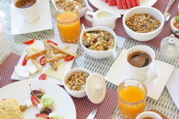 Beautifully arranged breakfast table with coffee, orange juice, pastry, fruits, cereals and eggs, top view	